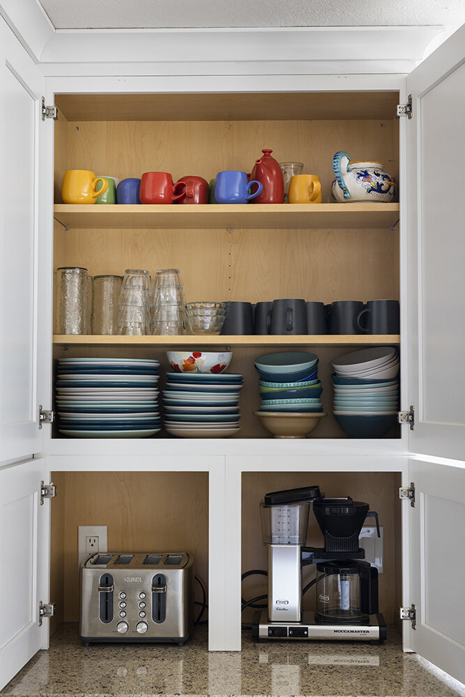 Kitchen cabinet stocked with colorful dishes and mugs