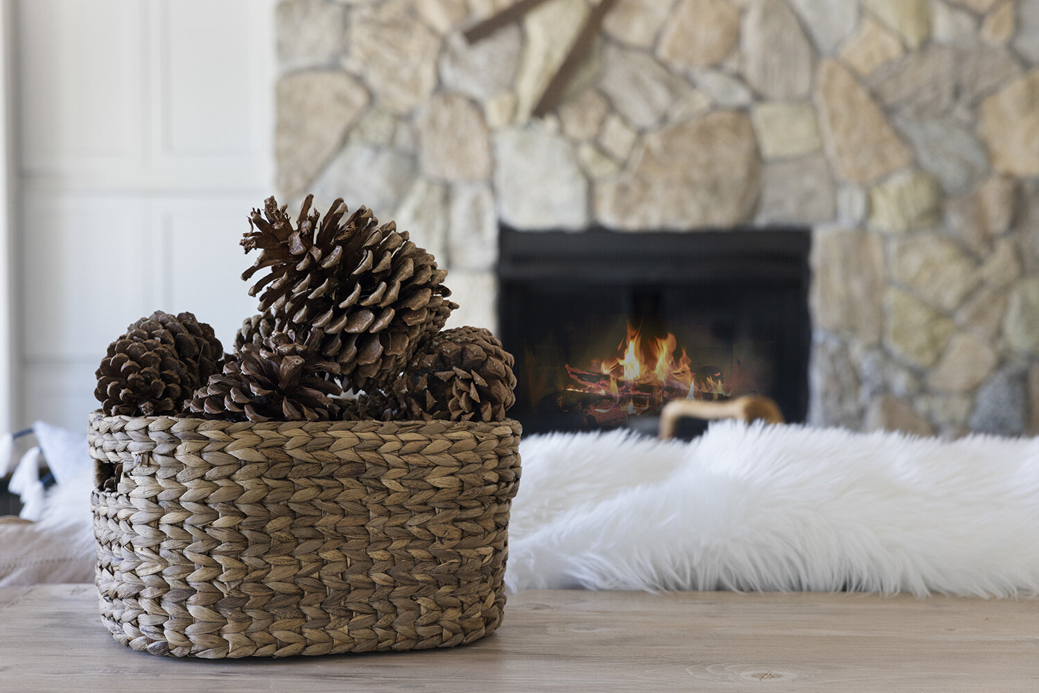 Basket of pinecones on the hearth with the fire lit behind