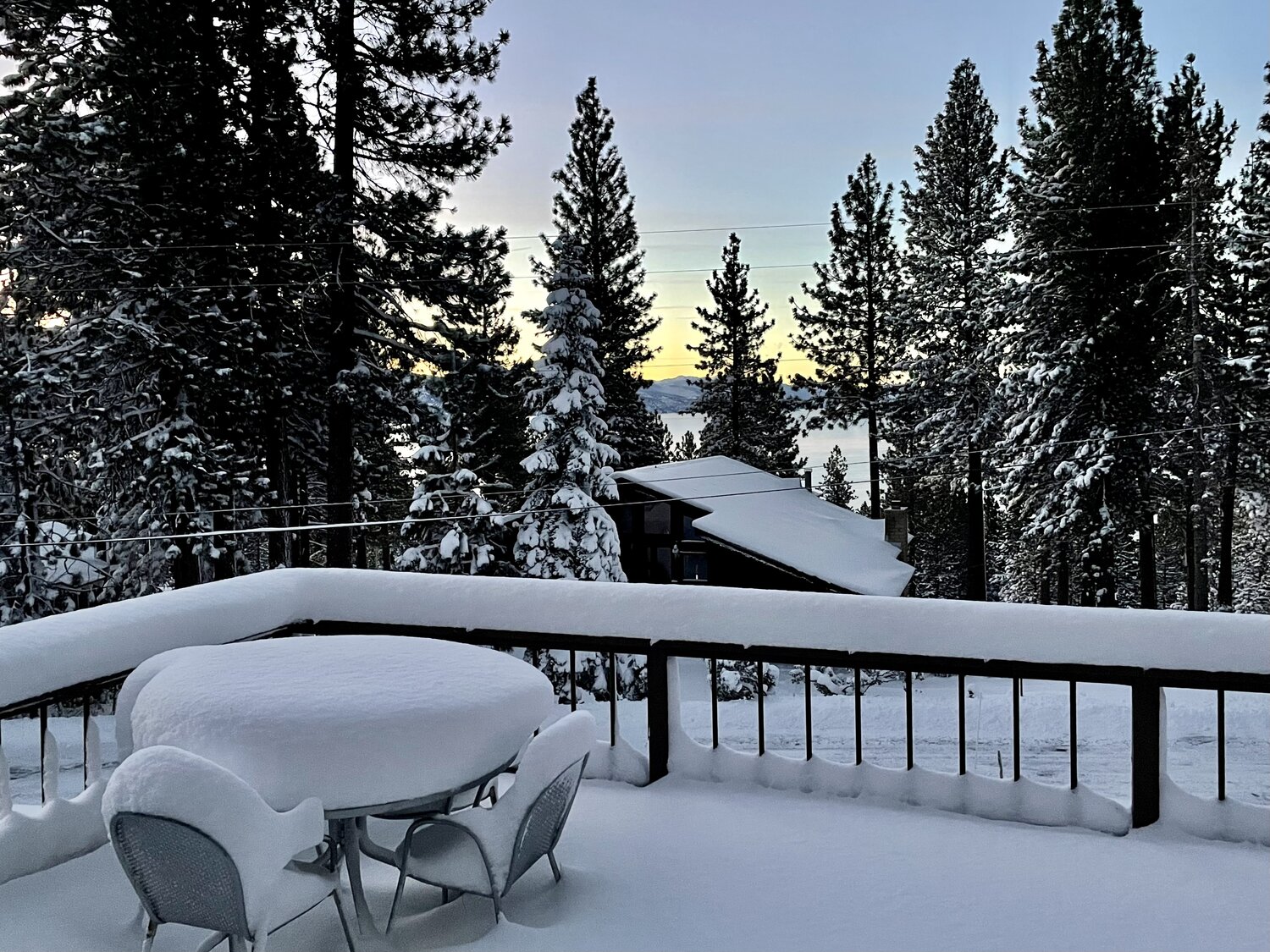 Snow-covered deck table at Kinpine House with Lake Tahoe visible at dusk